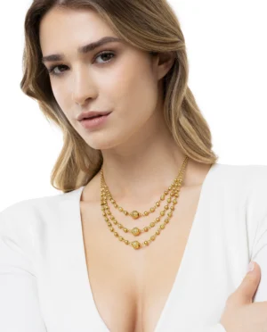 La collana in ottone multifilo con 3 sfere luminose che scandiscono il ritmo di questa collana multifilo, creando punti luce che emergono tra una trama di piccole perle dorate.